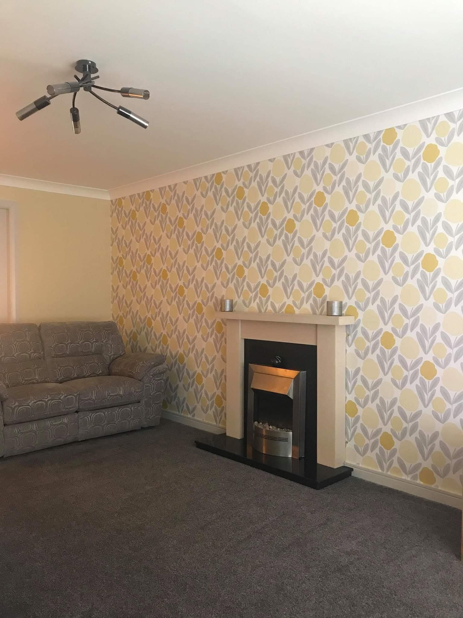 Gold and grey patterned wallpaper beside a fireplace